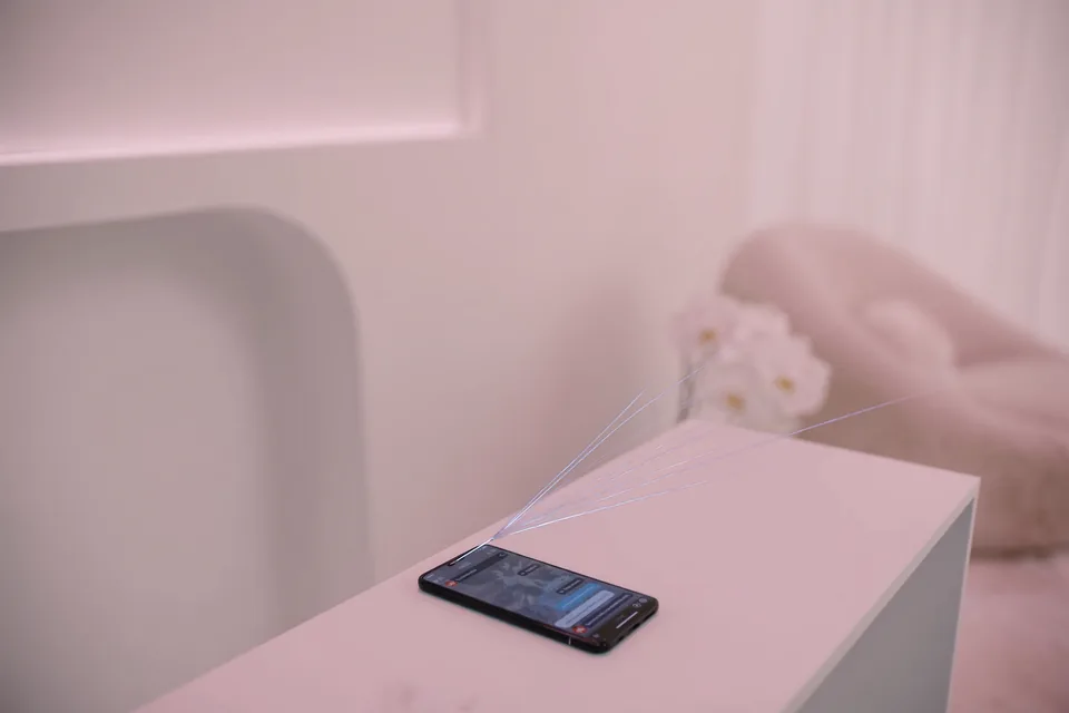 A phone on the counter of a pale pink aesthetic clinic, fine threads of light fanning out from it